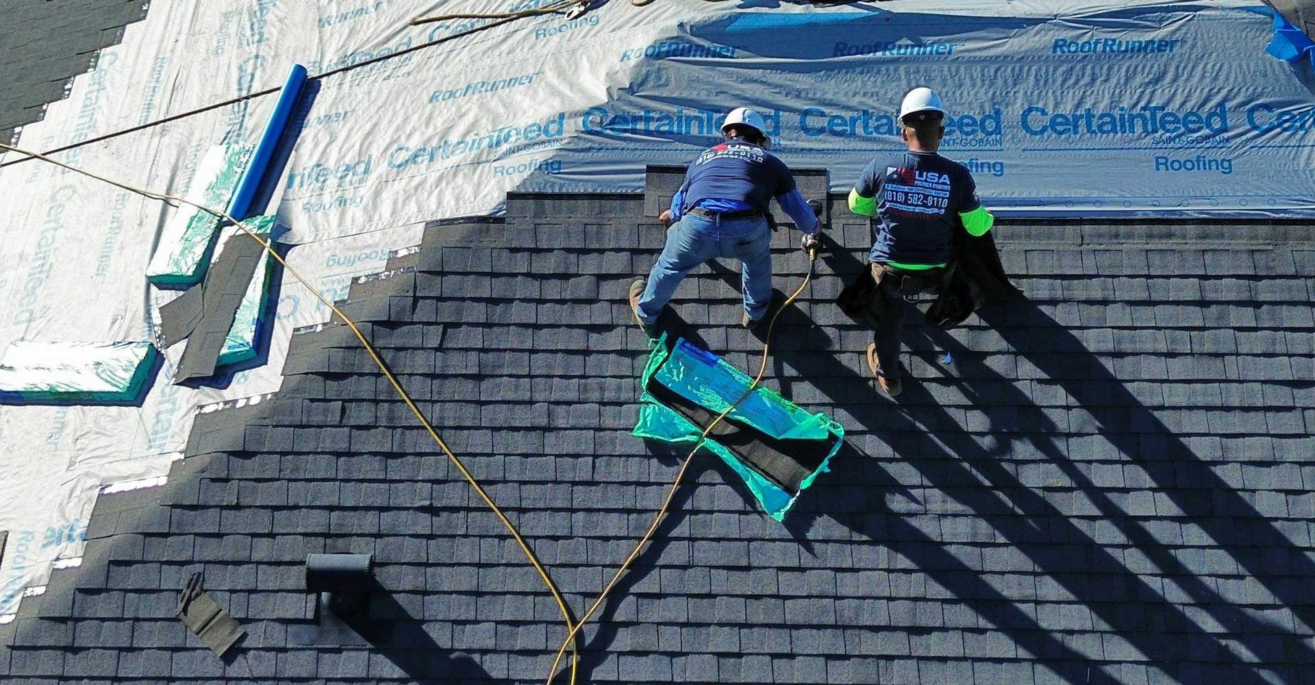 A pair of roofers installing a new roof on a home