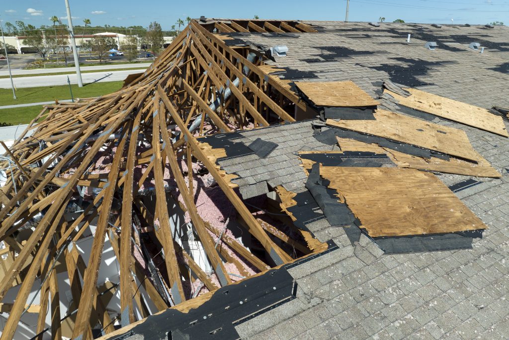 Severe roof damage requiring emergency roof repair Los Angeles with exposed wooden beams and missing shingles.