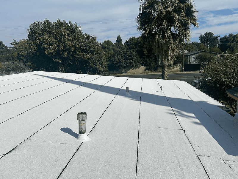 A white rooftop with a can placed on it and trees in the background.