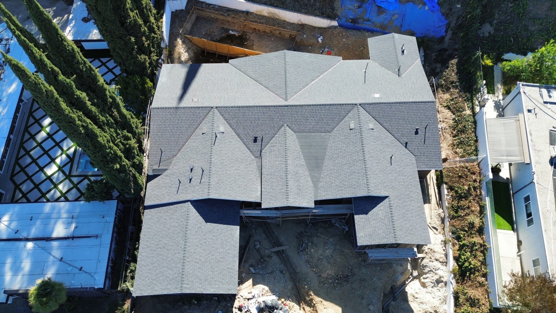 A large house with a grey multi-gabled roof under construction.