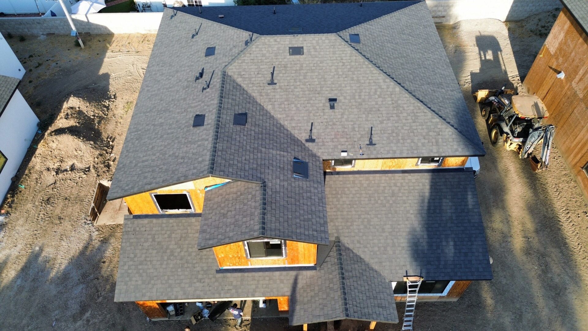 Aerial view of a house roof with new dark shingles.