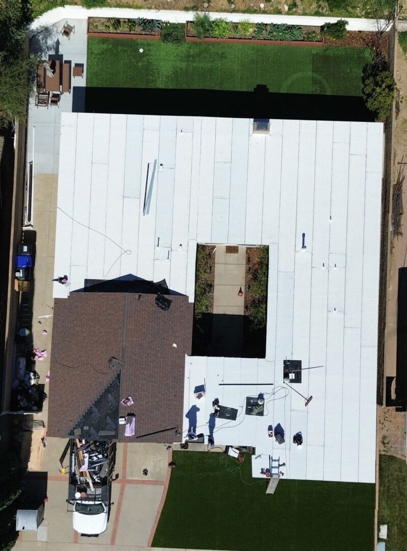 Aerial view of a building with a white roof and a brown section.