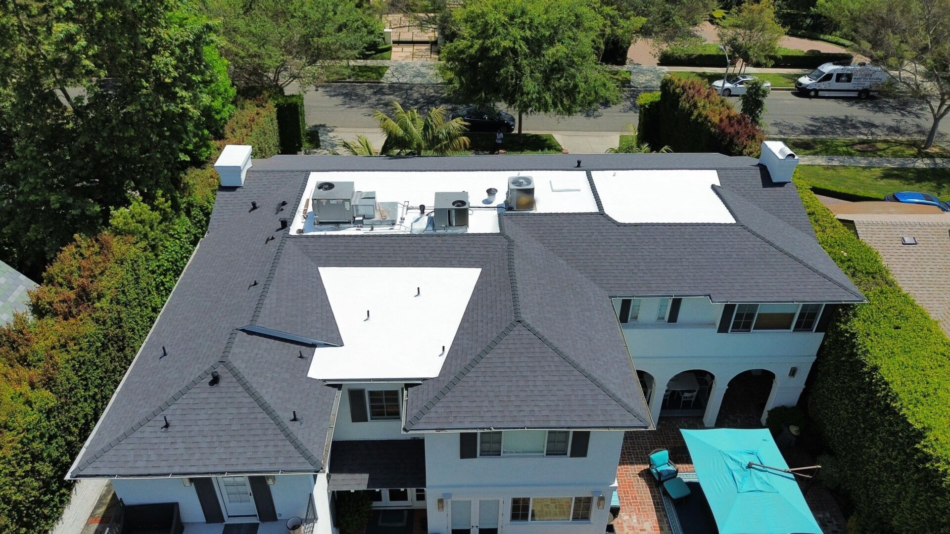 Aerial view of a building with multiple roof sections and surrounding greenery.