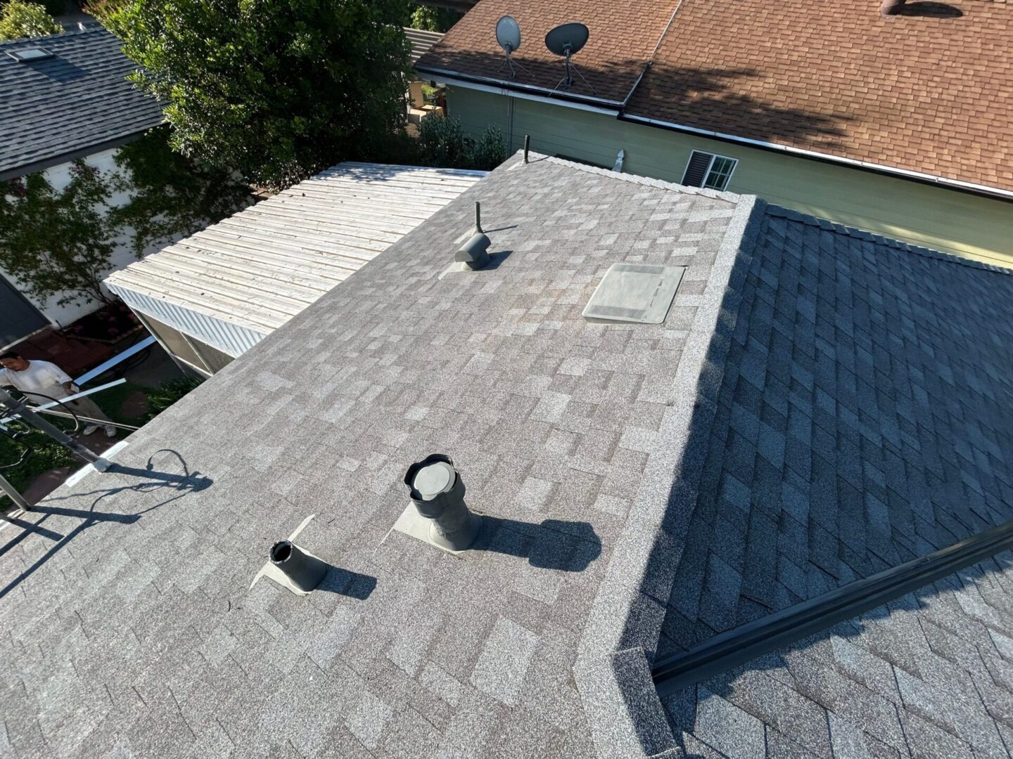 A roof with new asphalt shingles and ventilation pipes.