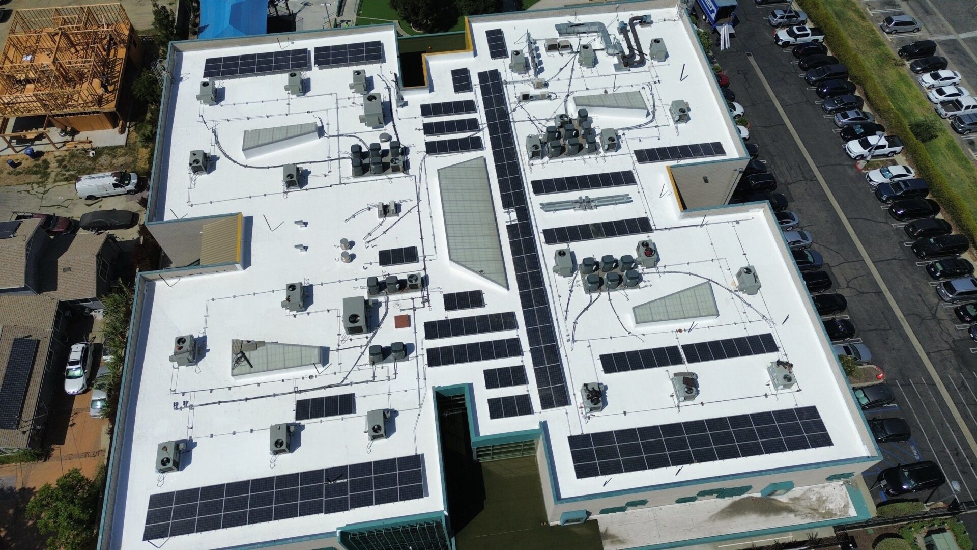 Aerial view of a white rooftop with solar panels and HVAC units.