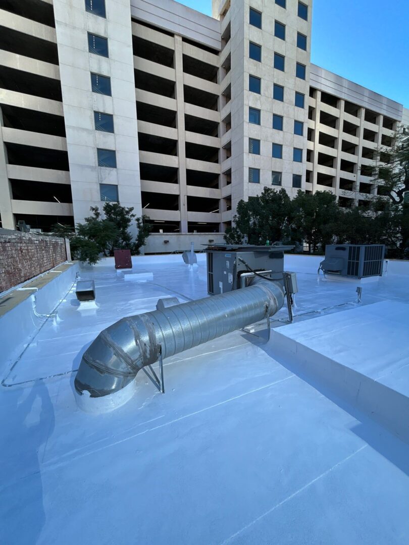 A building rooftop with HVAC ducts and white waterproof coating.