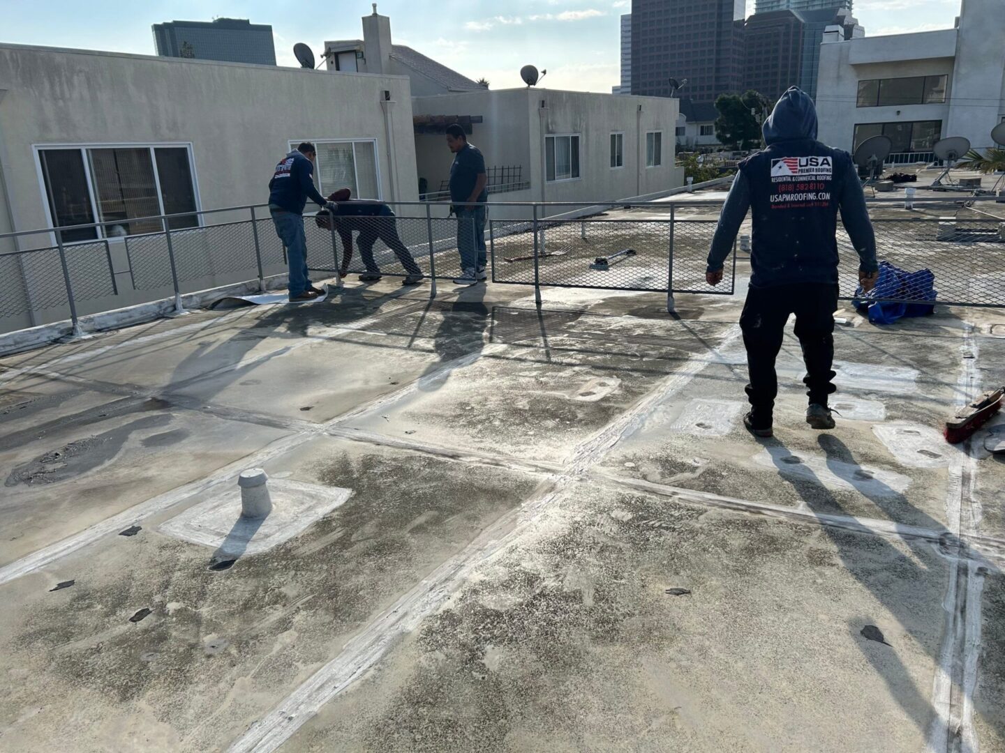 Workers preparing a concrete surface on a rooftop under sunny weather.