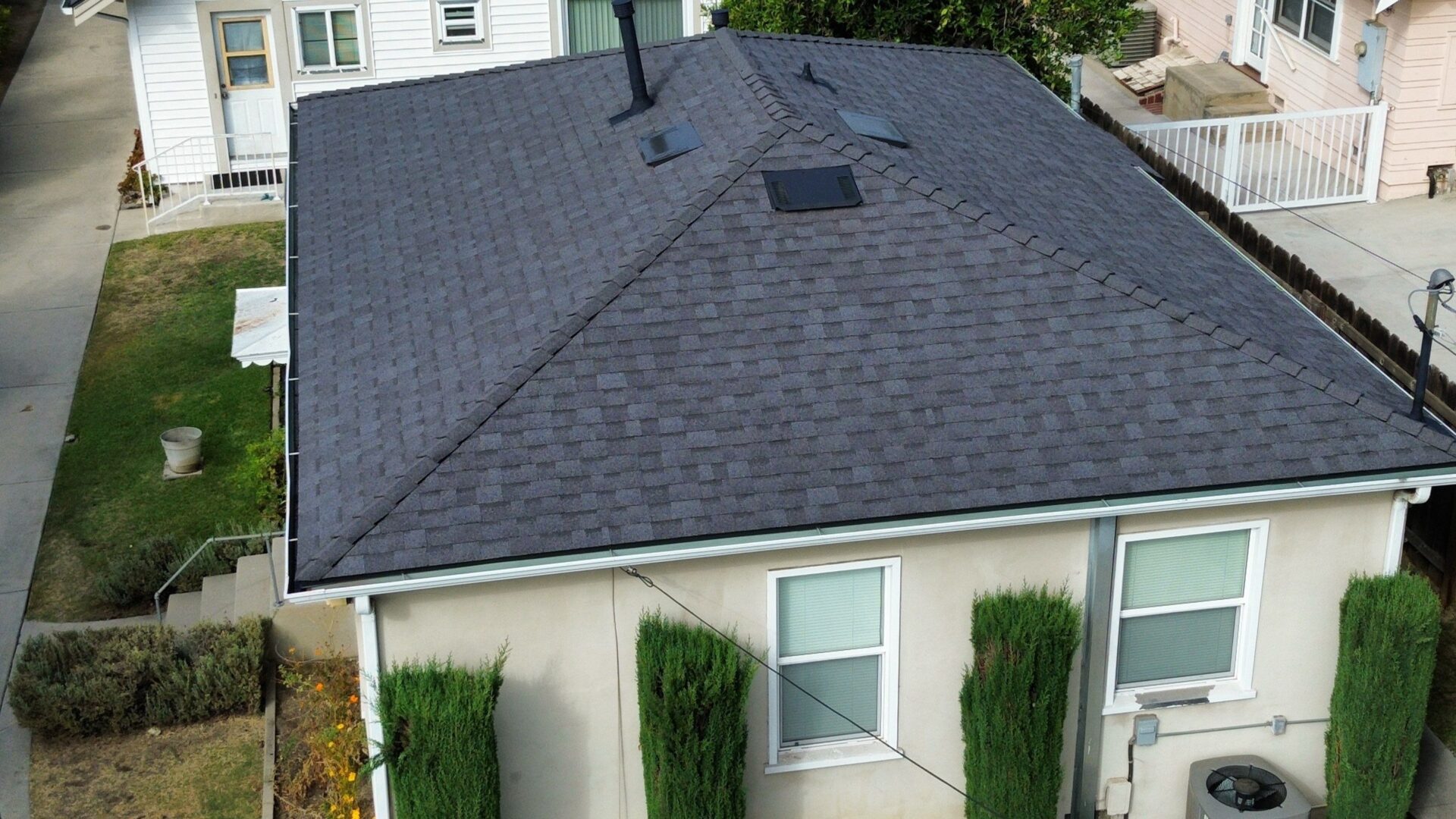 A house with a dark gray shingle roof and light-colored exterior walls.