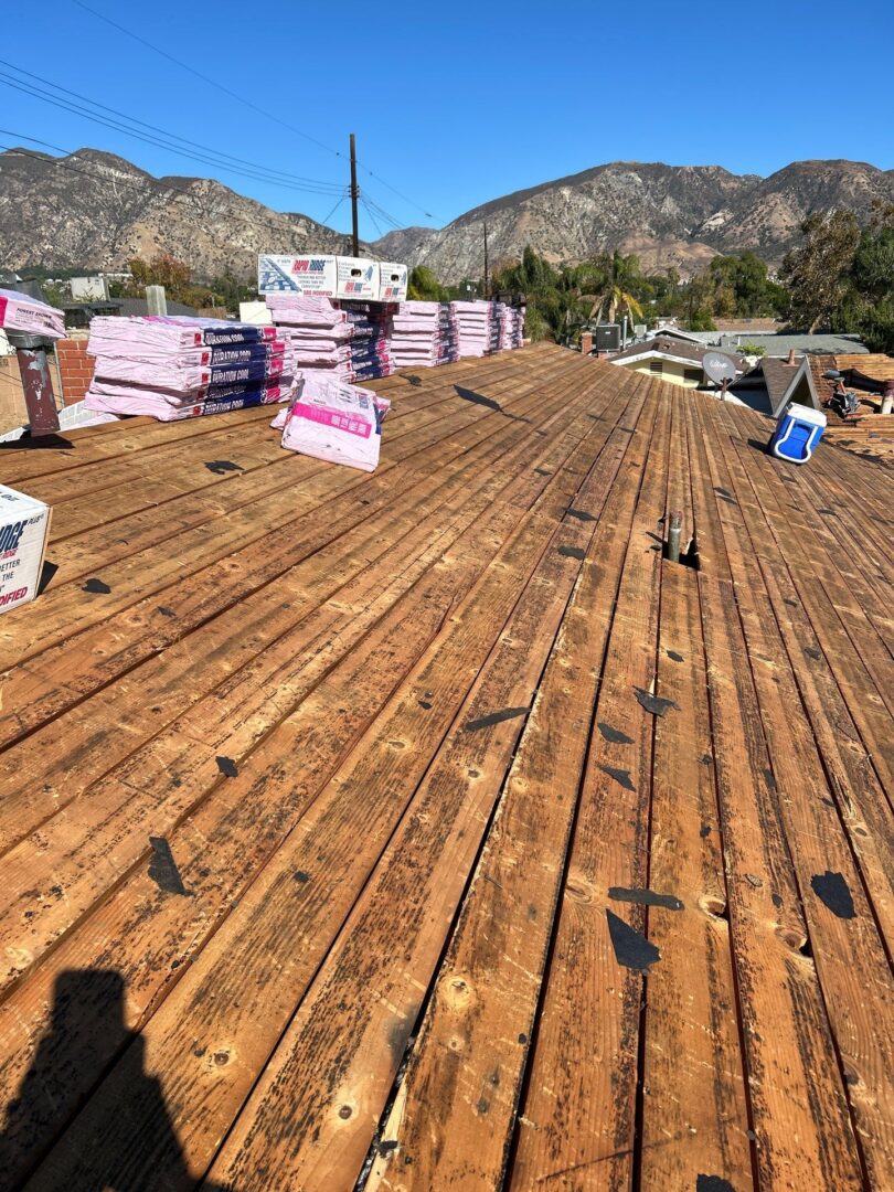 Newly sanded wooden deck with mountain backdrop and construction materials.