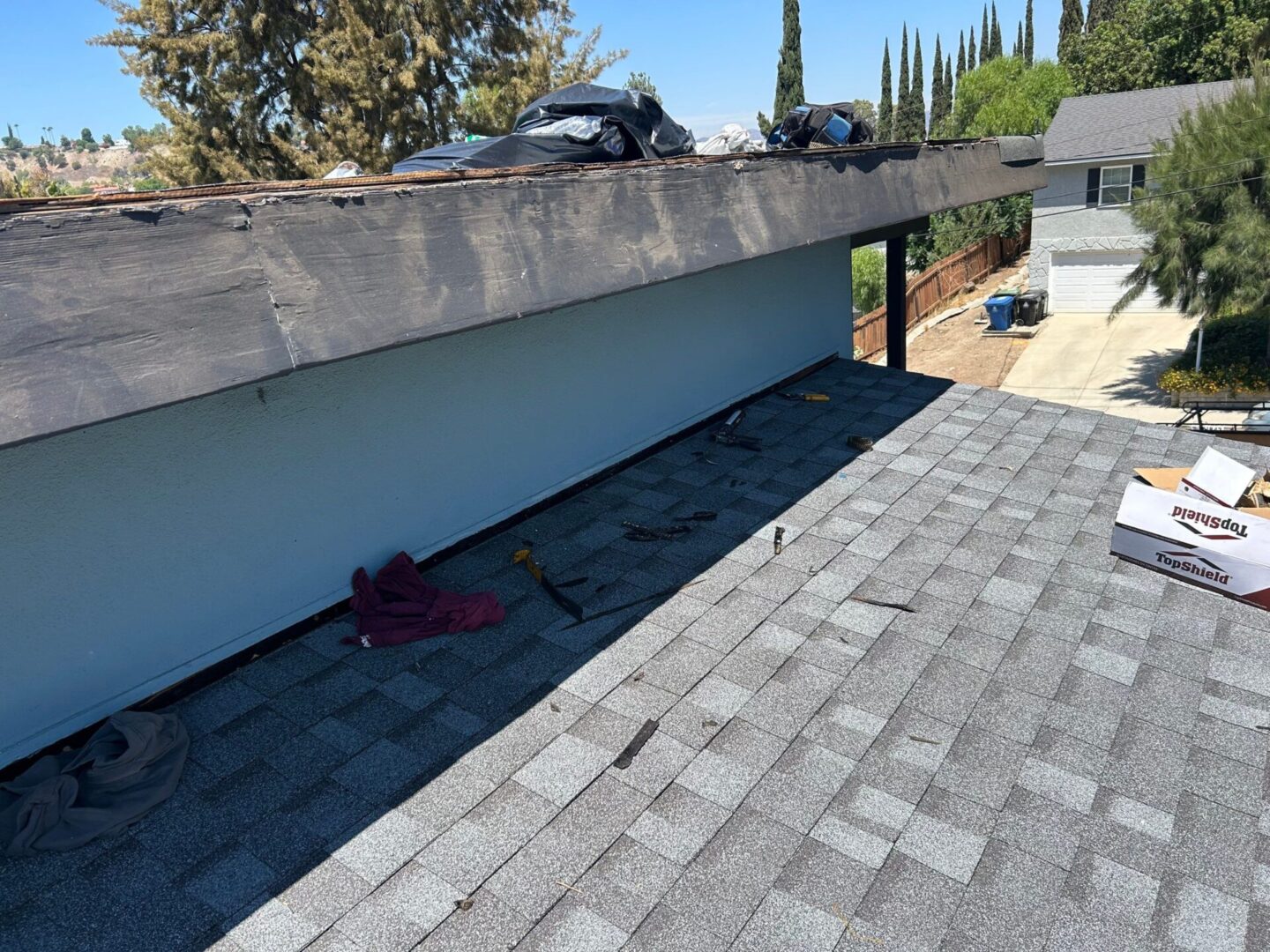Roof with damaged shingles and debris near the edge.