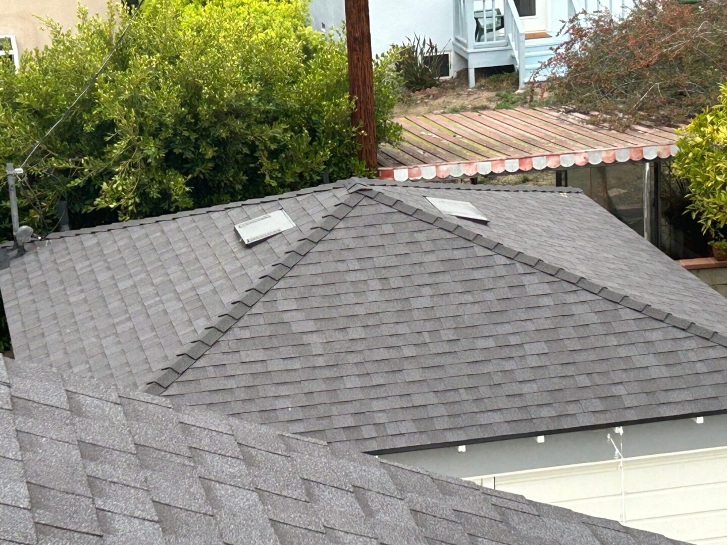 Gray roof with two loose shingles lying on top.