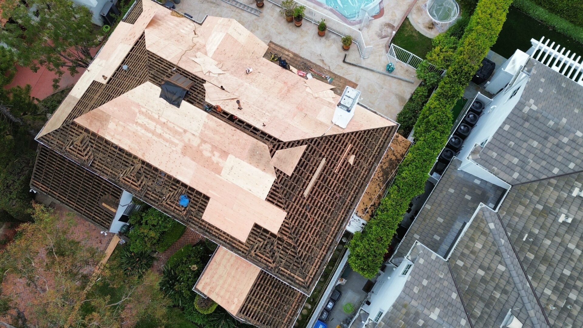 Aerial view of a residential house with a tiled roof and a pool.