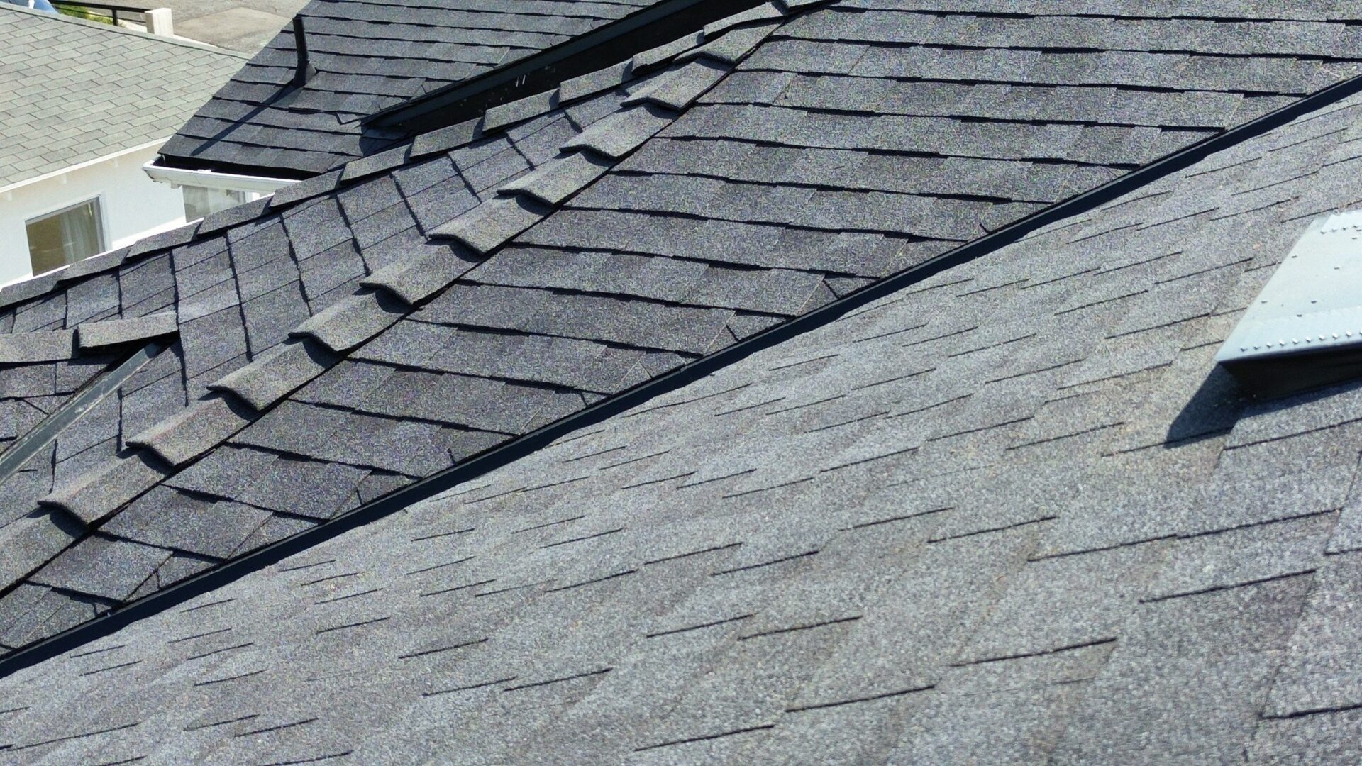 Close-up of gray asphalt roof shingles arranged in an overlapping pattern.