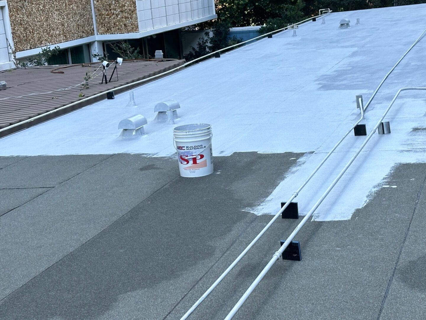 Workers applying white waterproof coating on a flat rooftop.