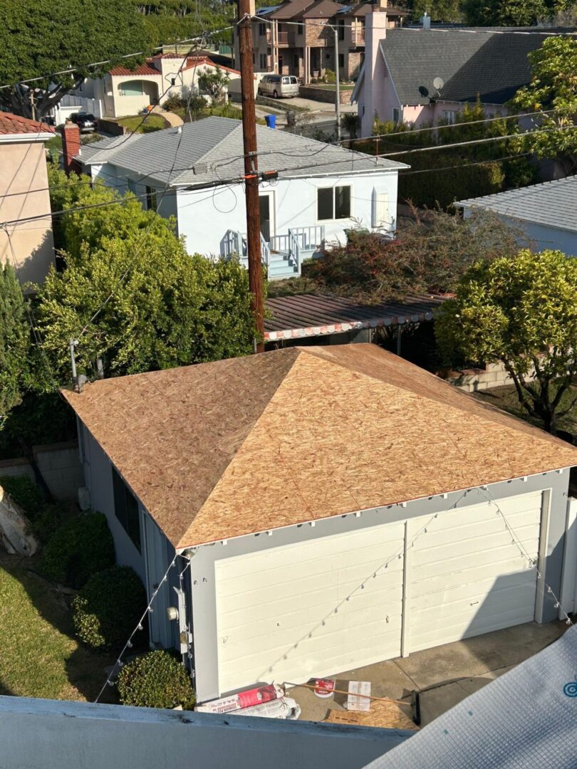 Newly constructed detached garage with wooden shingle roof in a residential area.