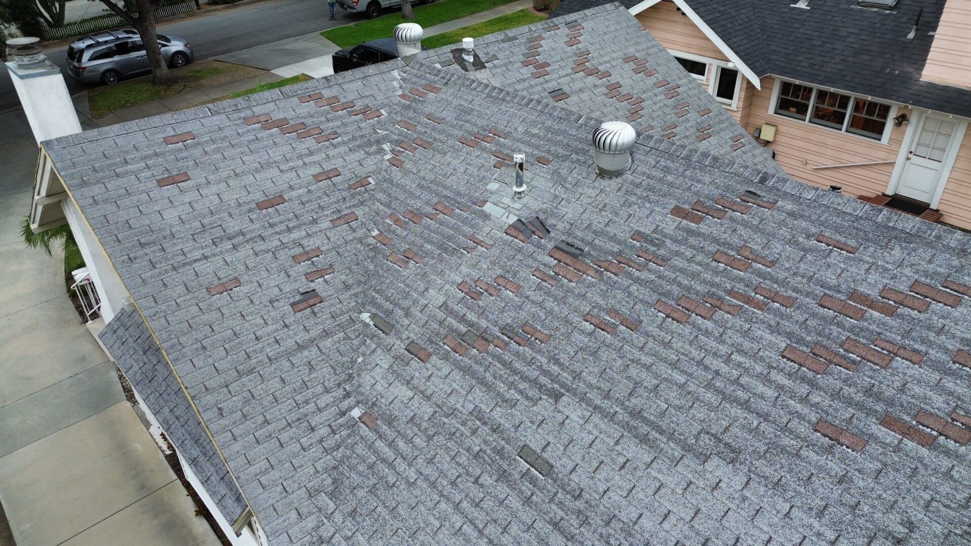A rooftop with old, worn shingles and multiple vents.