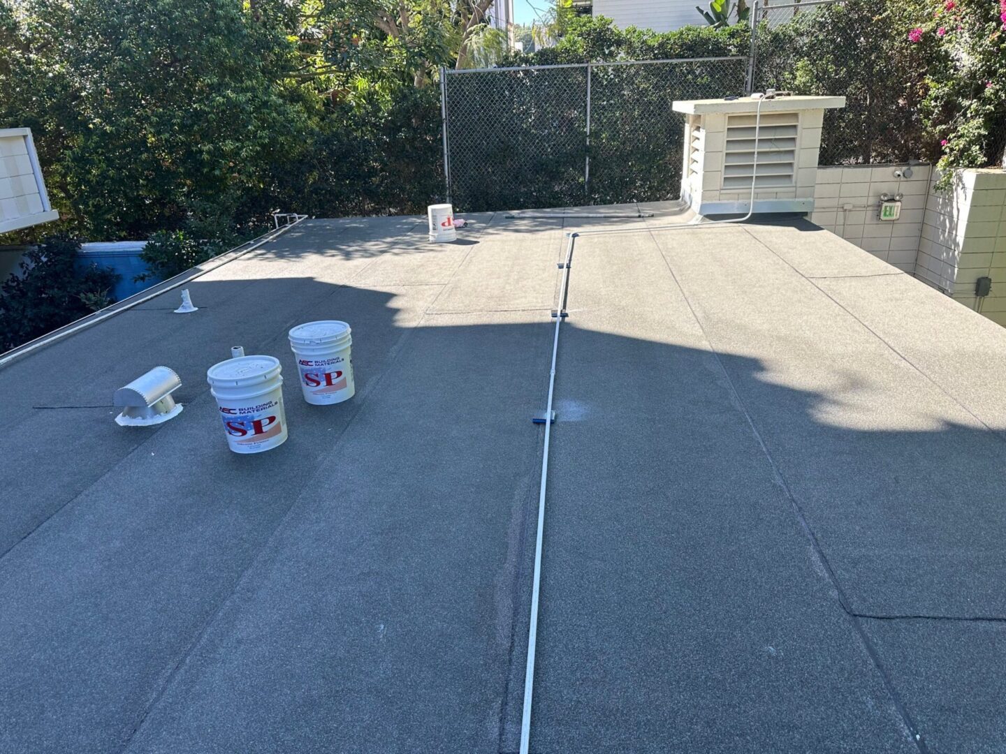 Roofing work in progress with buckets and tools on a flat roof.