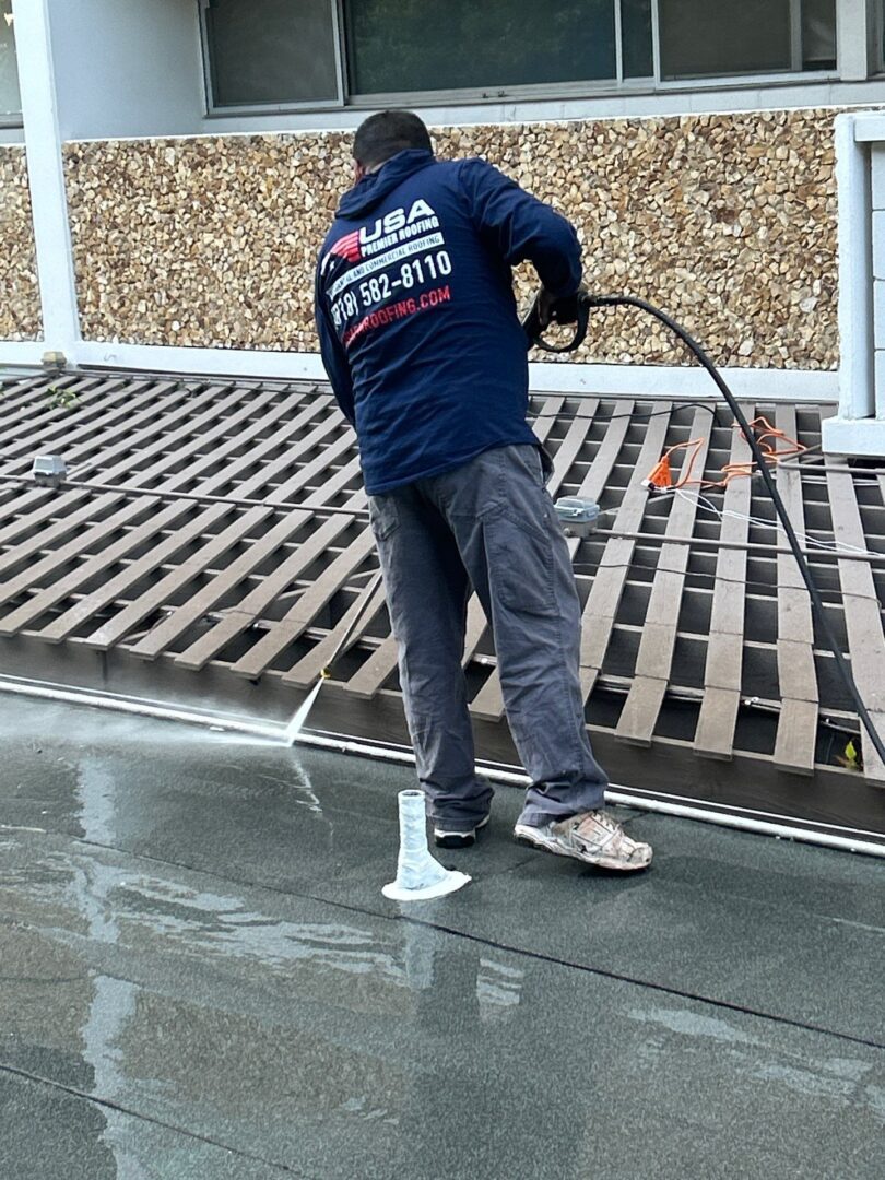 Worker cleaning a tiled roof with a pressure washer.