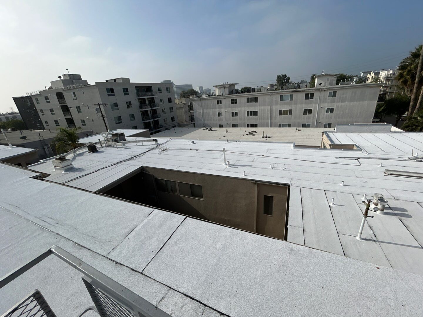 Flat rooftops covered with a white waterproofing layer in an urban area.