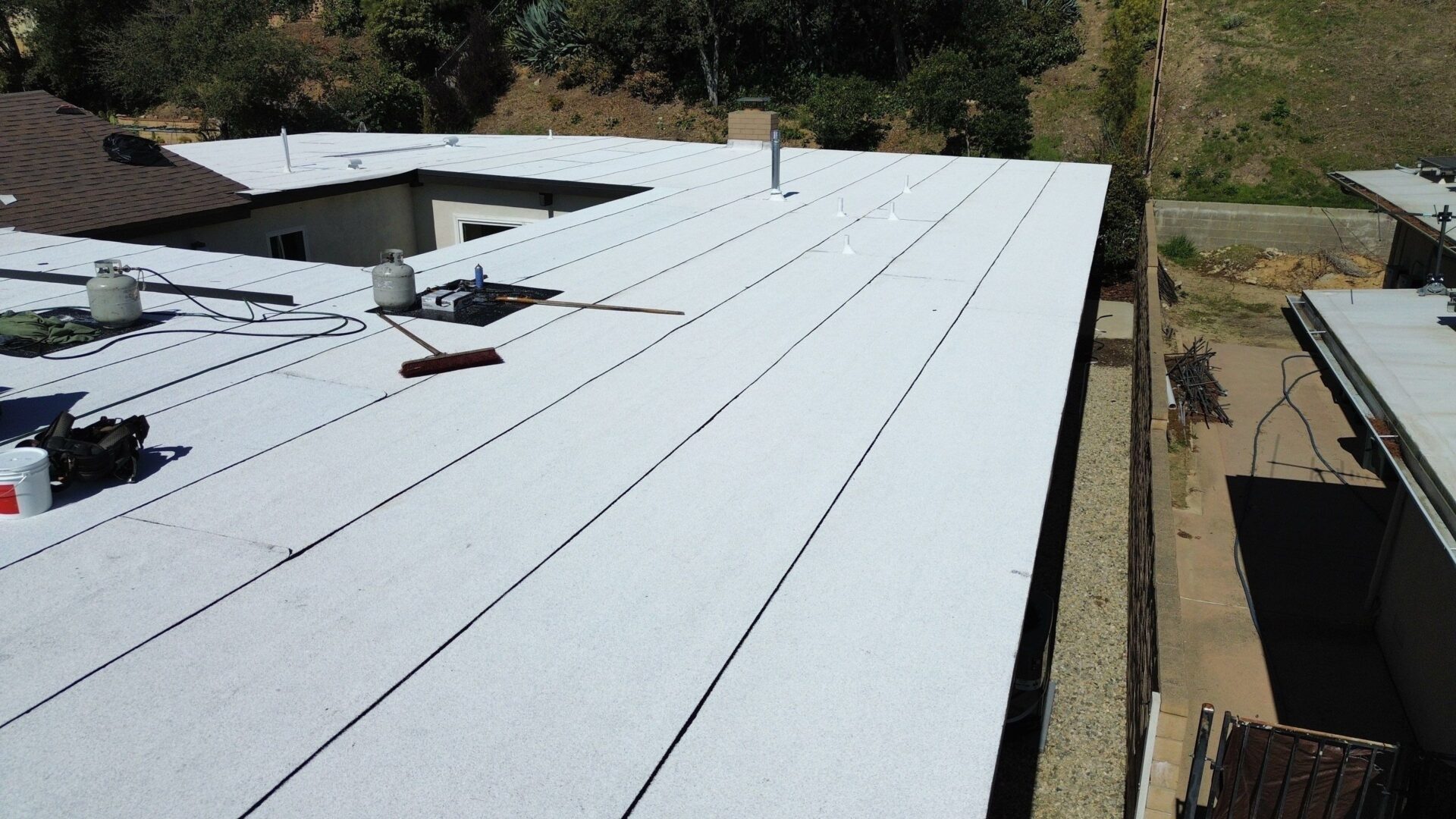 Flat white roof with clean, straight lines and tools scattered on the surface.