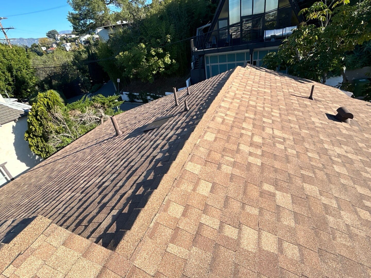 New roof installation showing shingles and vents under clear sky.