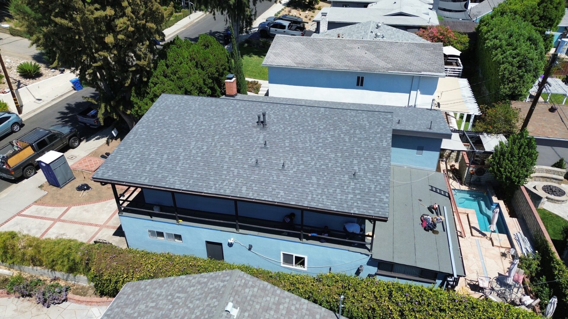 Aerial view of houses with gray roofs and blue walls in a residential area.