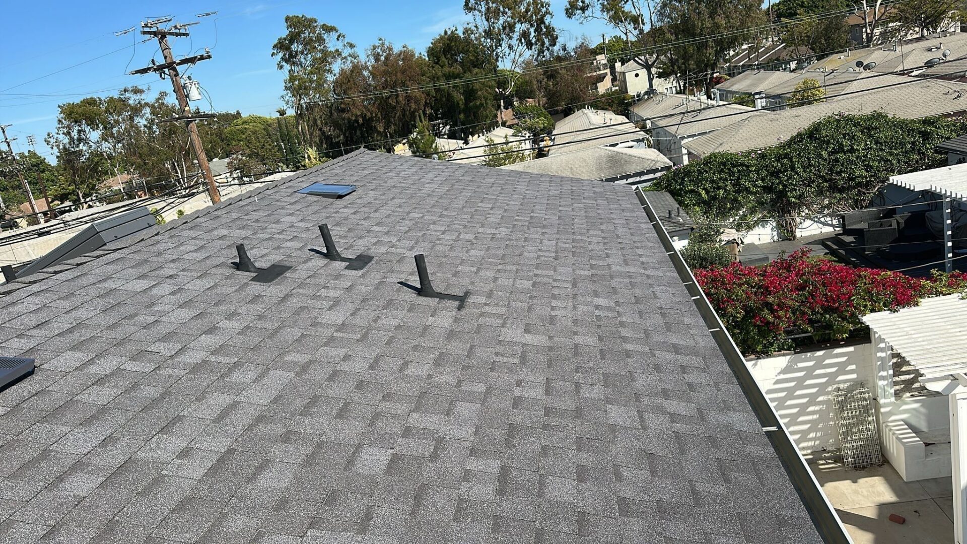 Newly installed gray shingle roof with ventilation pipes.