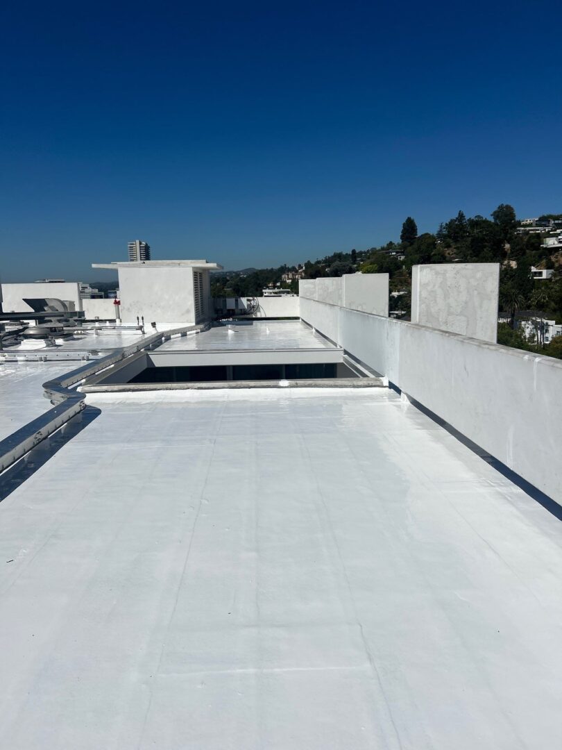 Newly coated white rooftop reflecting clear blue sky.