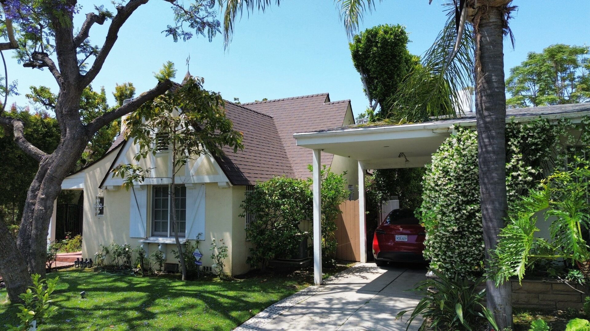 Cozy single-story house with a carport and lush greenery.