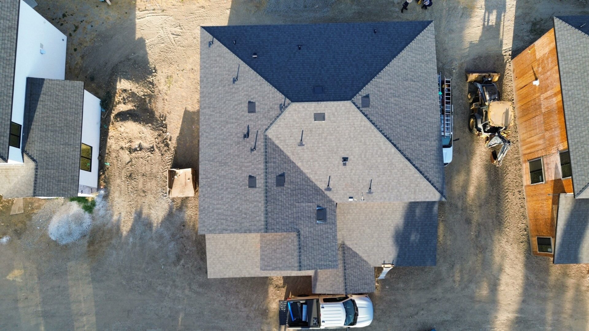Aerial view of a house with a gray shingled roof and parked car.