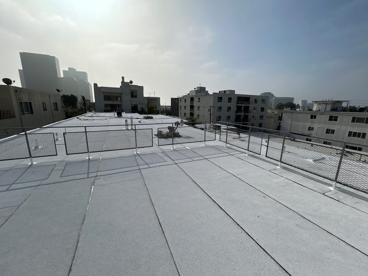 Sunlit rooftop with surrounding buildings under a hazy sky.