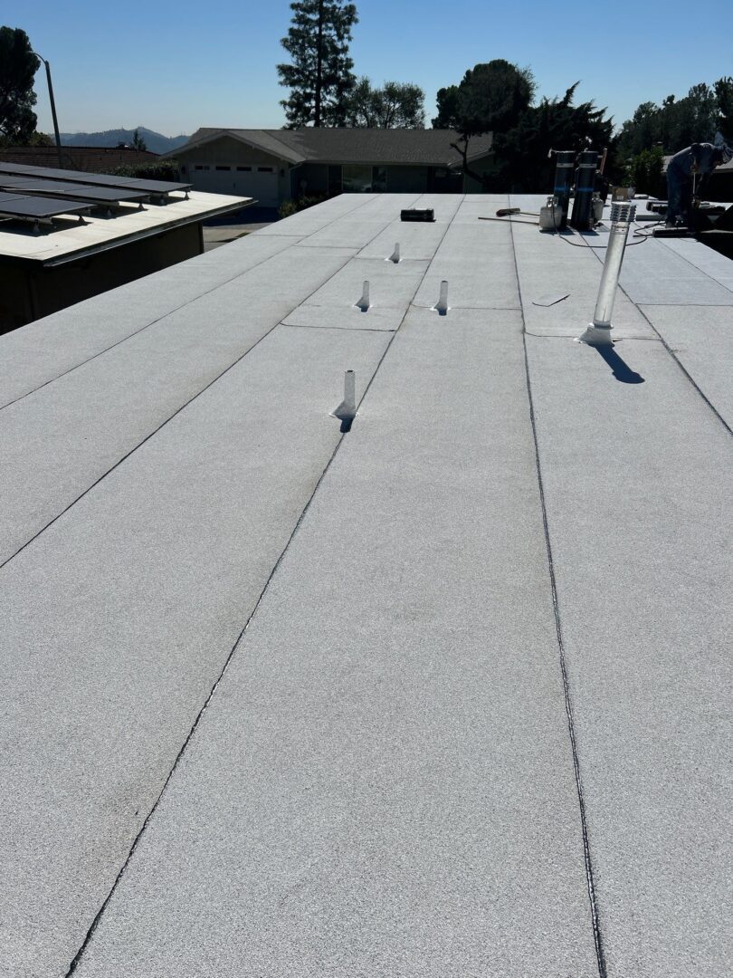 Flat rooftop with multiple metal rods and vents under a clear sky.