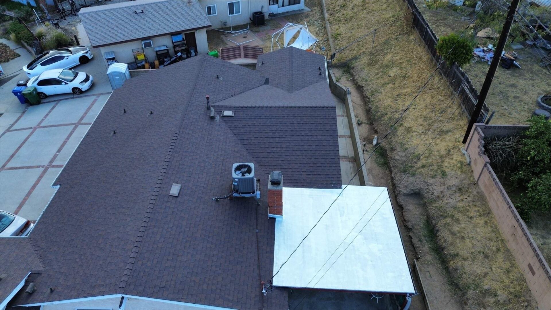 Aerial view of a house roof with HVAC units and a small extension.