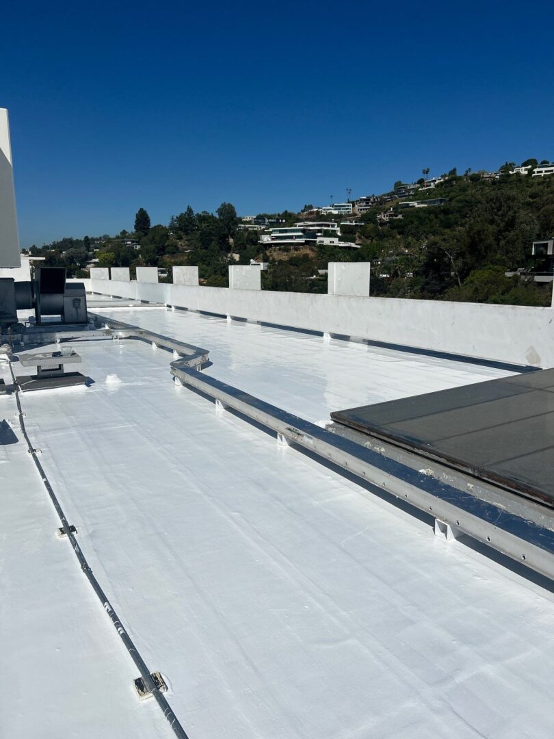 A white rooftop with pipes and a clear blue sky.