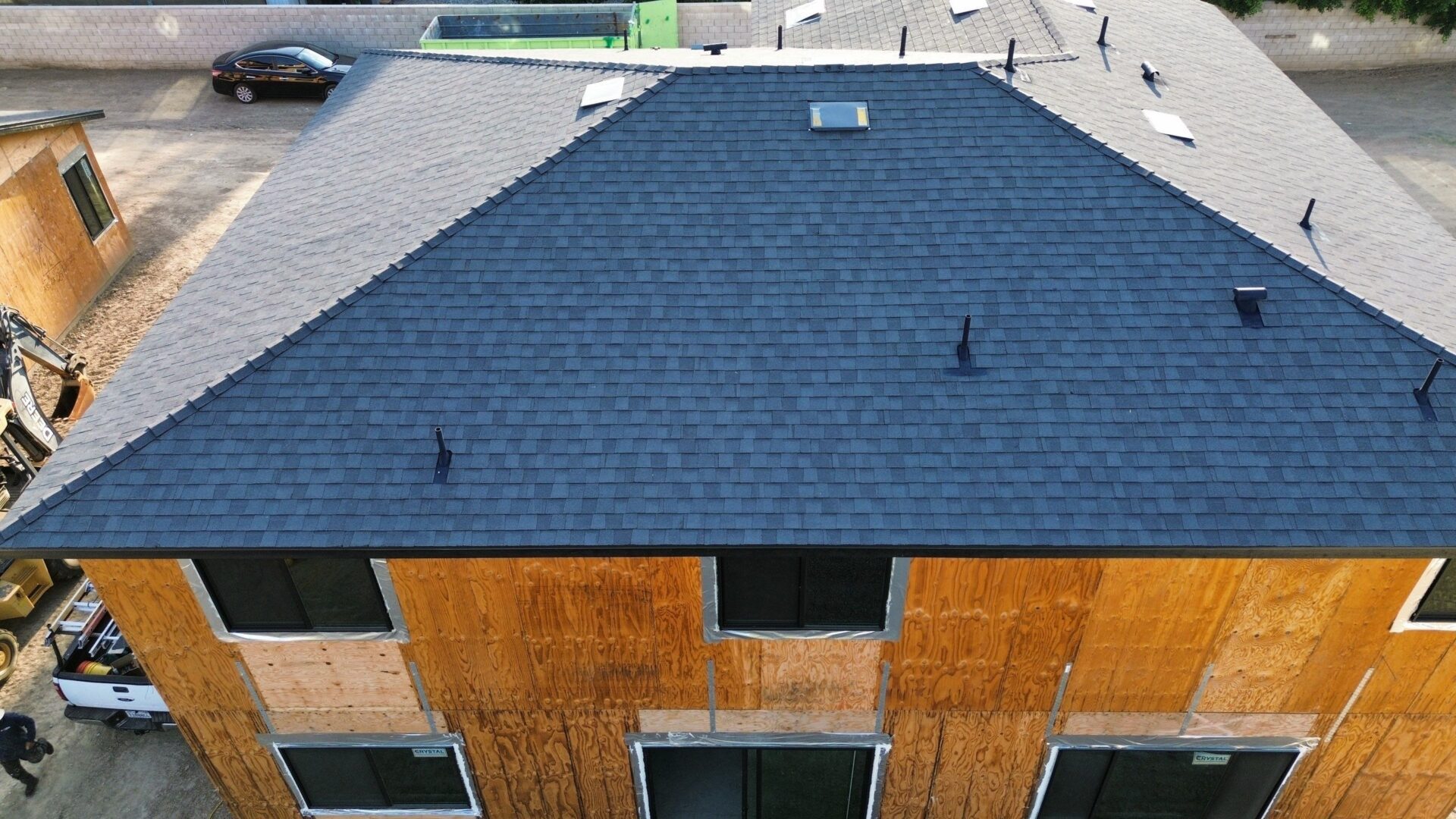 Aerial view of a house with a dark shingle roof and wooden siding.