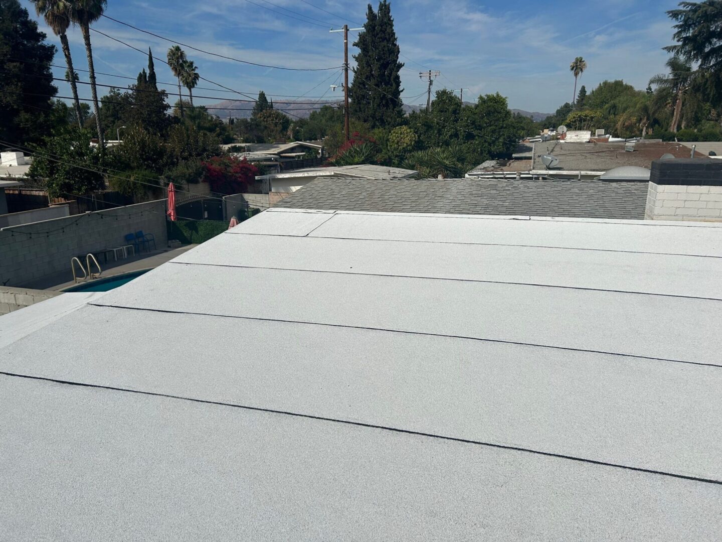 A flat roof covered with white insulating panels under a blue sky.