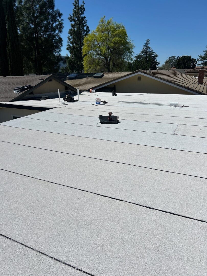 A flat roof with new white waterproof membrane and rooftop vents.