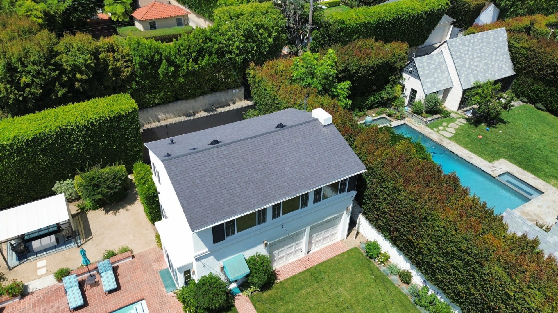 Aerial view of a modern house with a dark roof and green lawn.