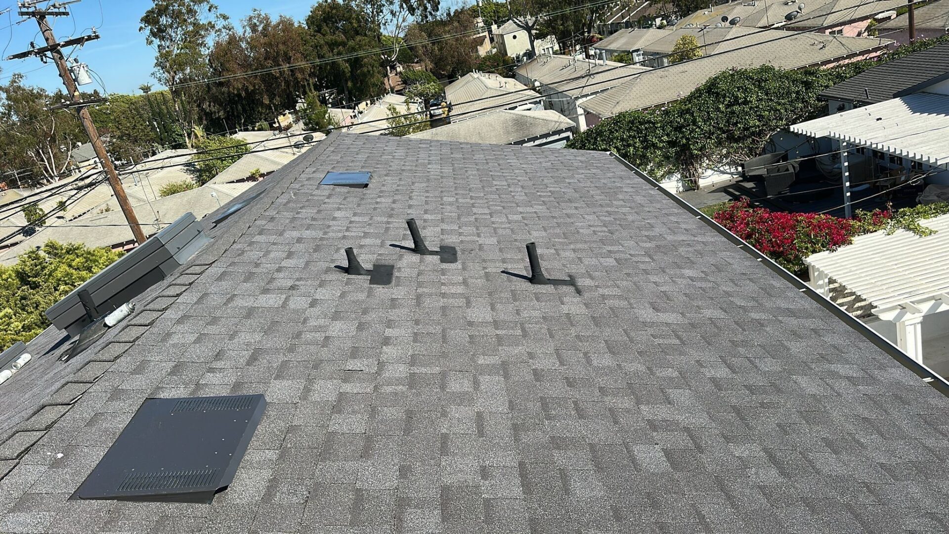 Newly installed asphalt shingle roof with three vent pipes.