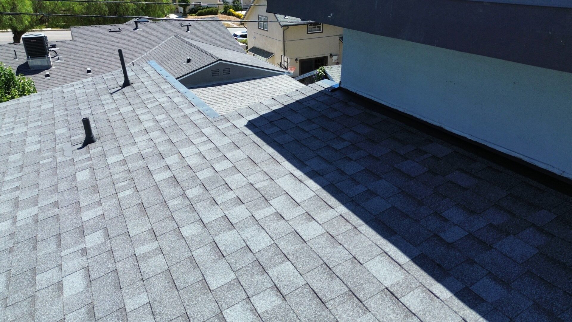 A rooftop with newly installed asphalt shingles under clear daylight.