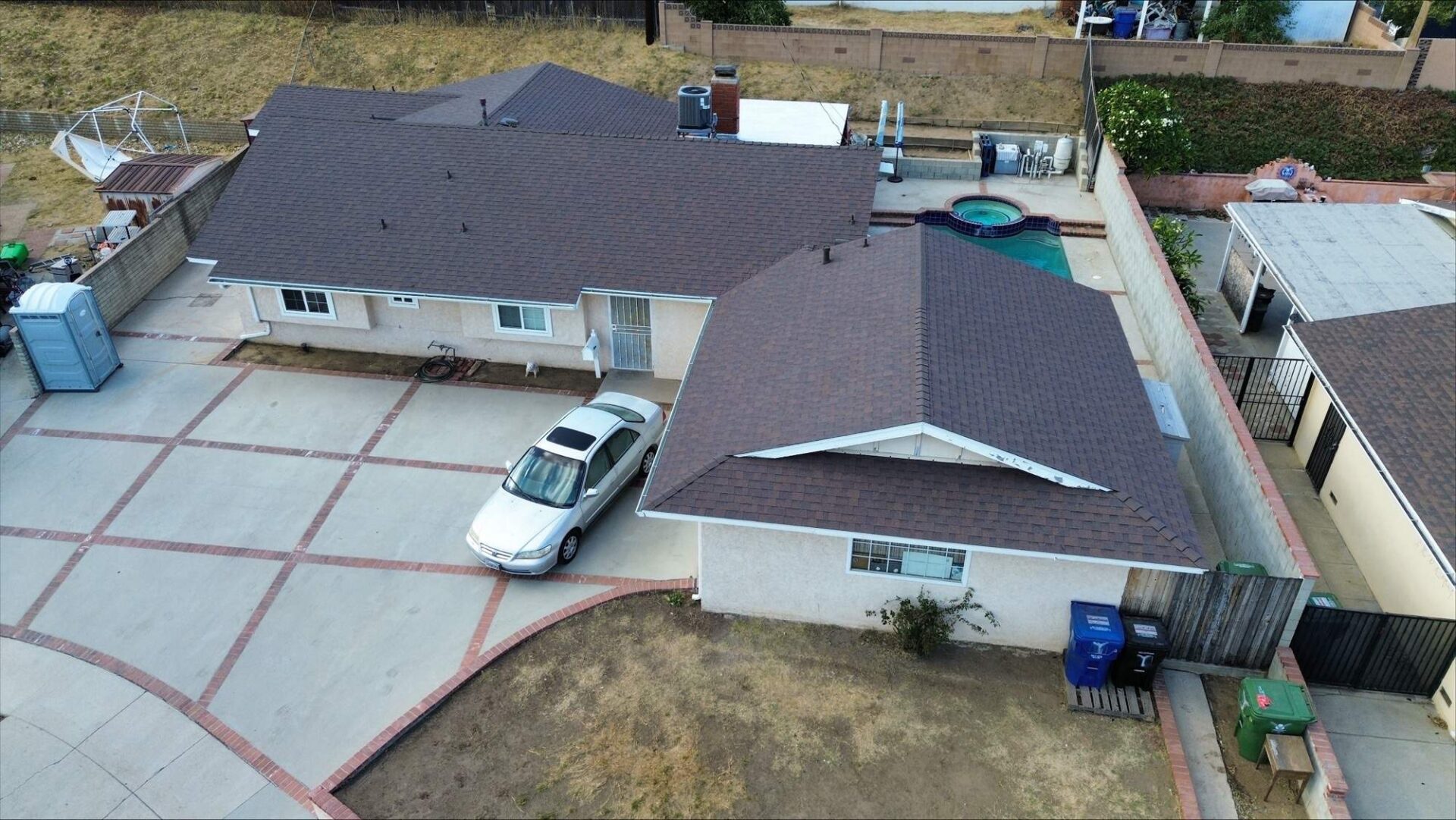 Aerial view of a residential driveway with a white car parked.