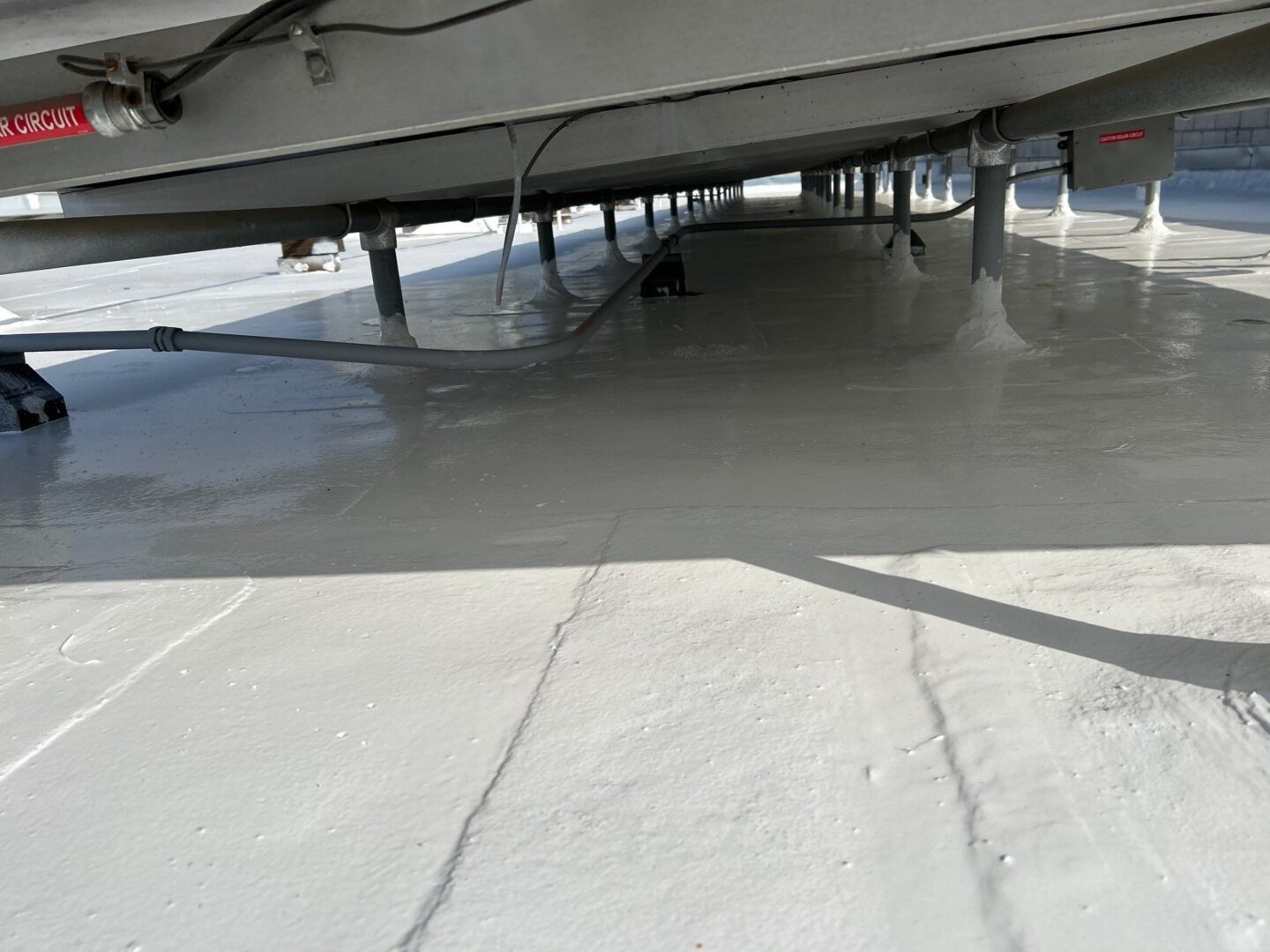 Freshly applied smooth white epoxy flooring under a building structure.