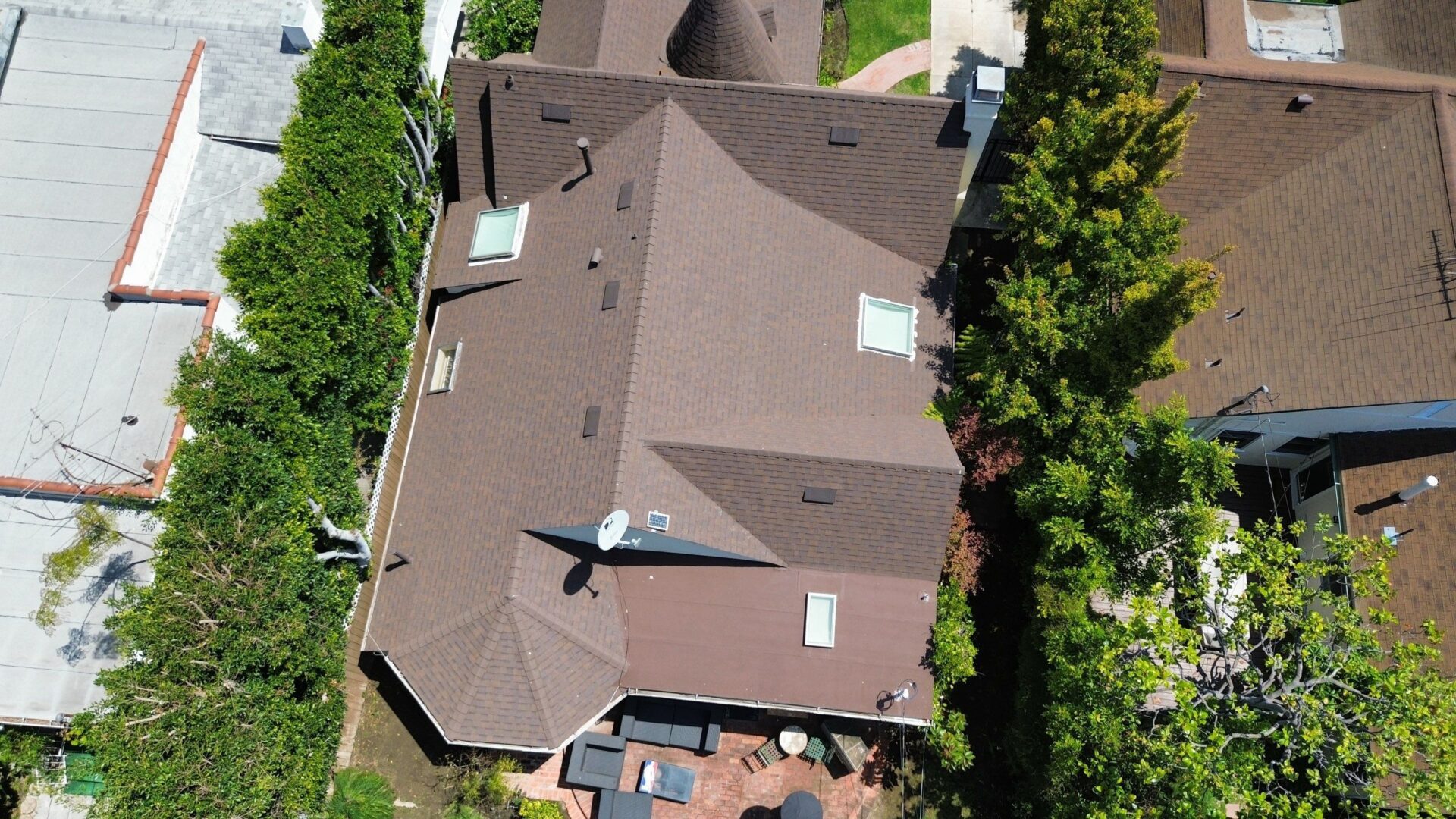 Aerial view of a large residential house with a brown roof and surrounding greenery.