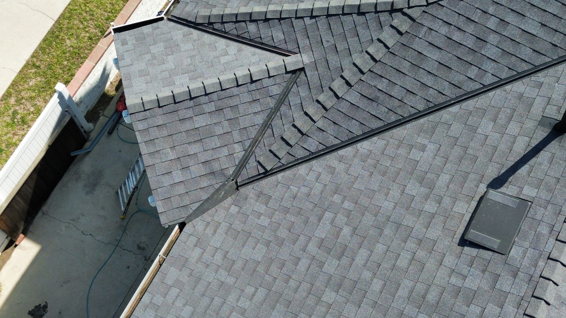 Aerial view of a complex grey shingle roof with multiple slopes and ridges.