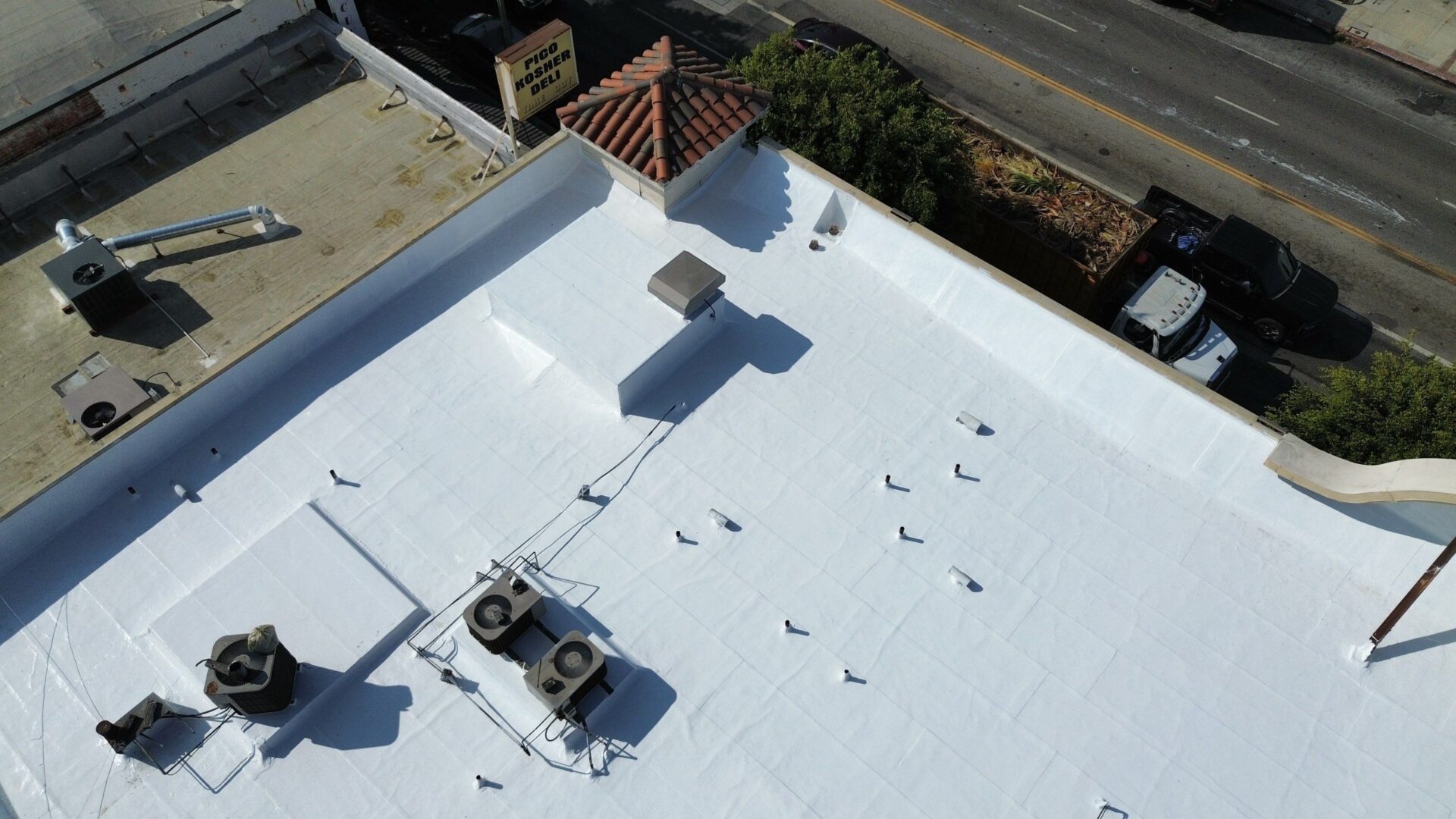A white flat rooftop with HVAC units and vents.