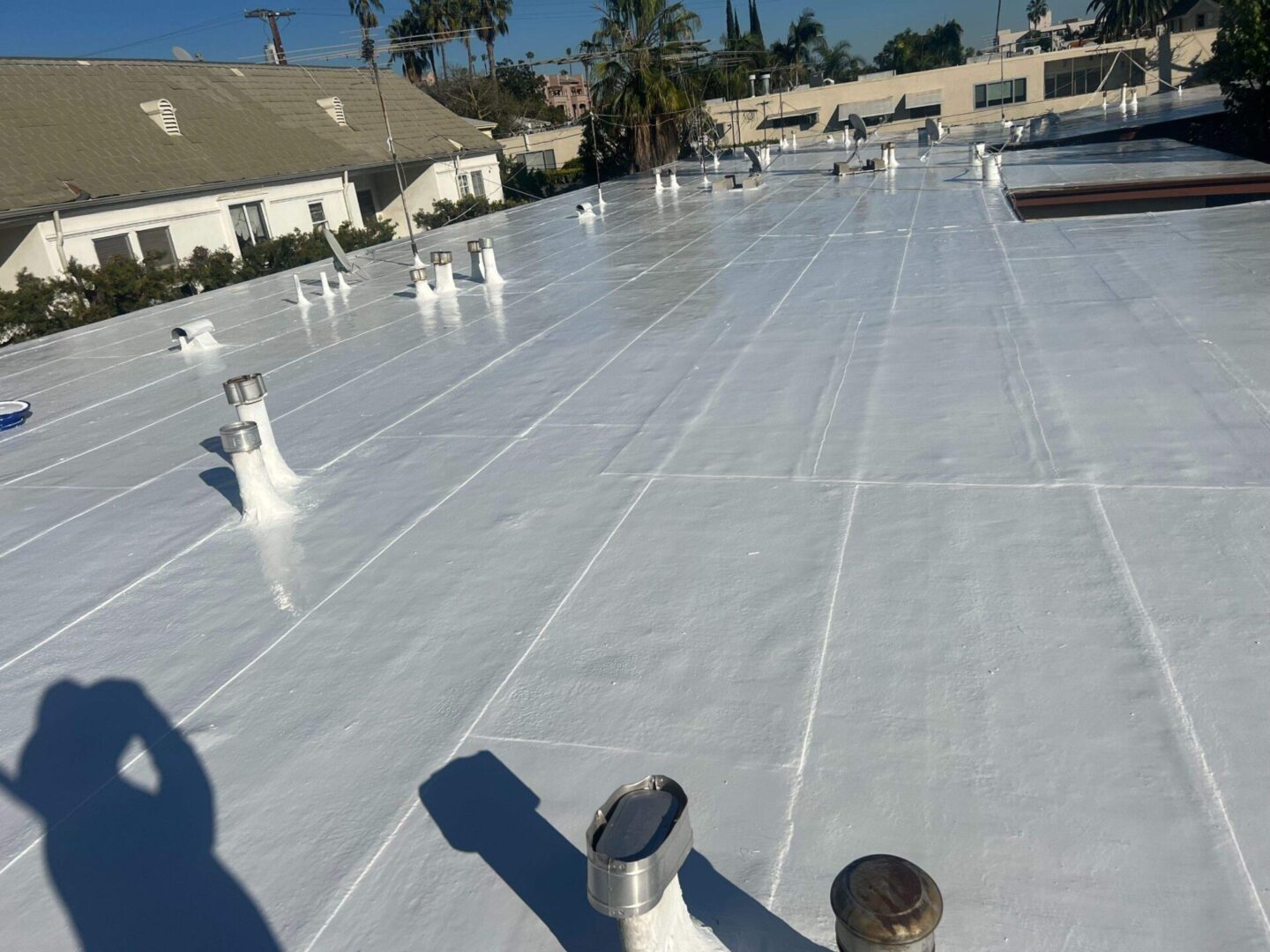 Clean, white commercial flat roof with vents and pipes.