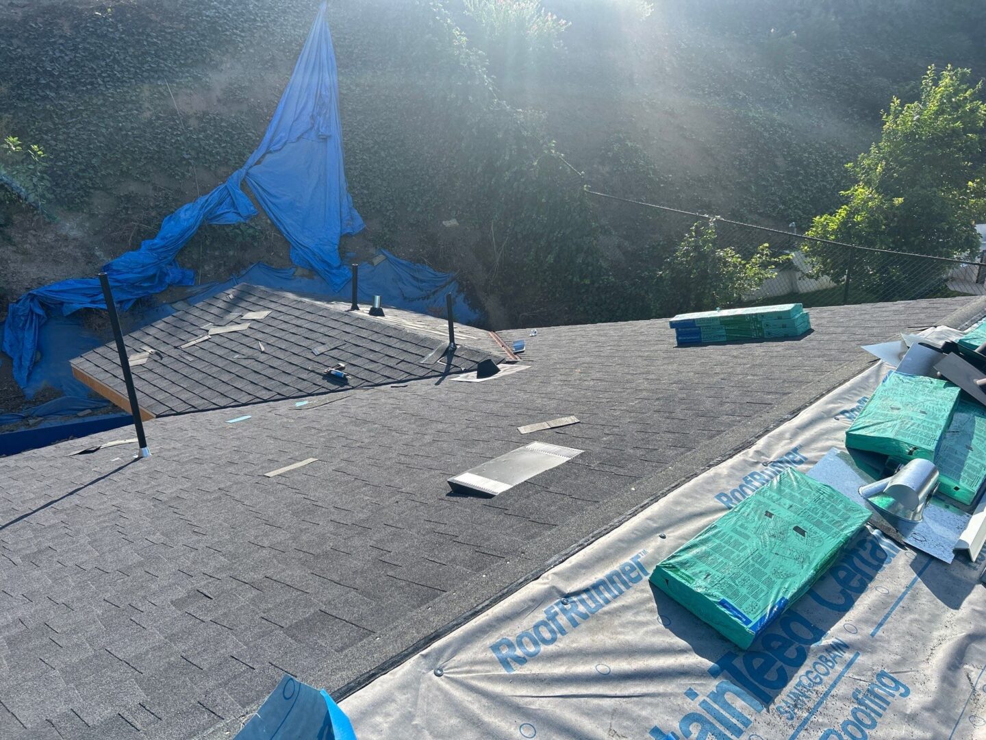 Workers installing new shingles on a sunny rooftop.