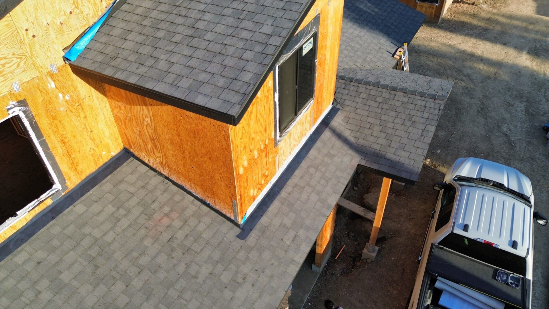 A close-up view of a house roof with shingles and a dormer window.