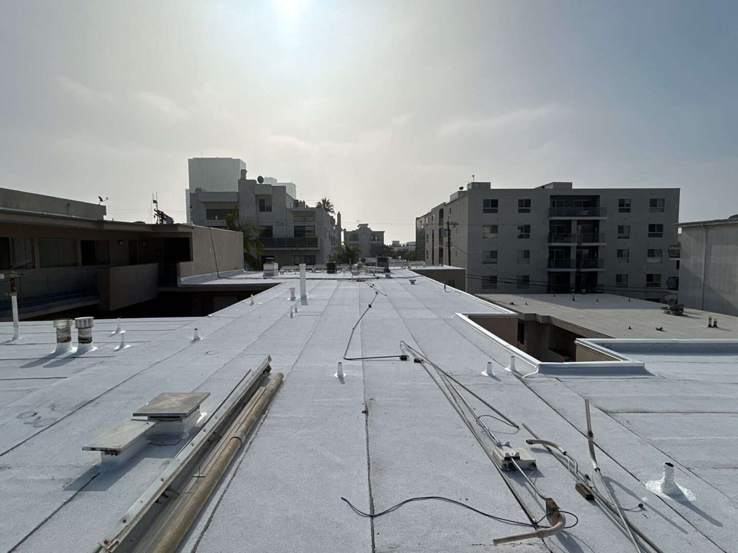 Flat rooftop with various cables and buildings under a hazy sky.
