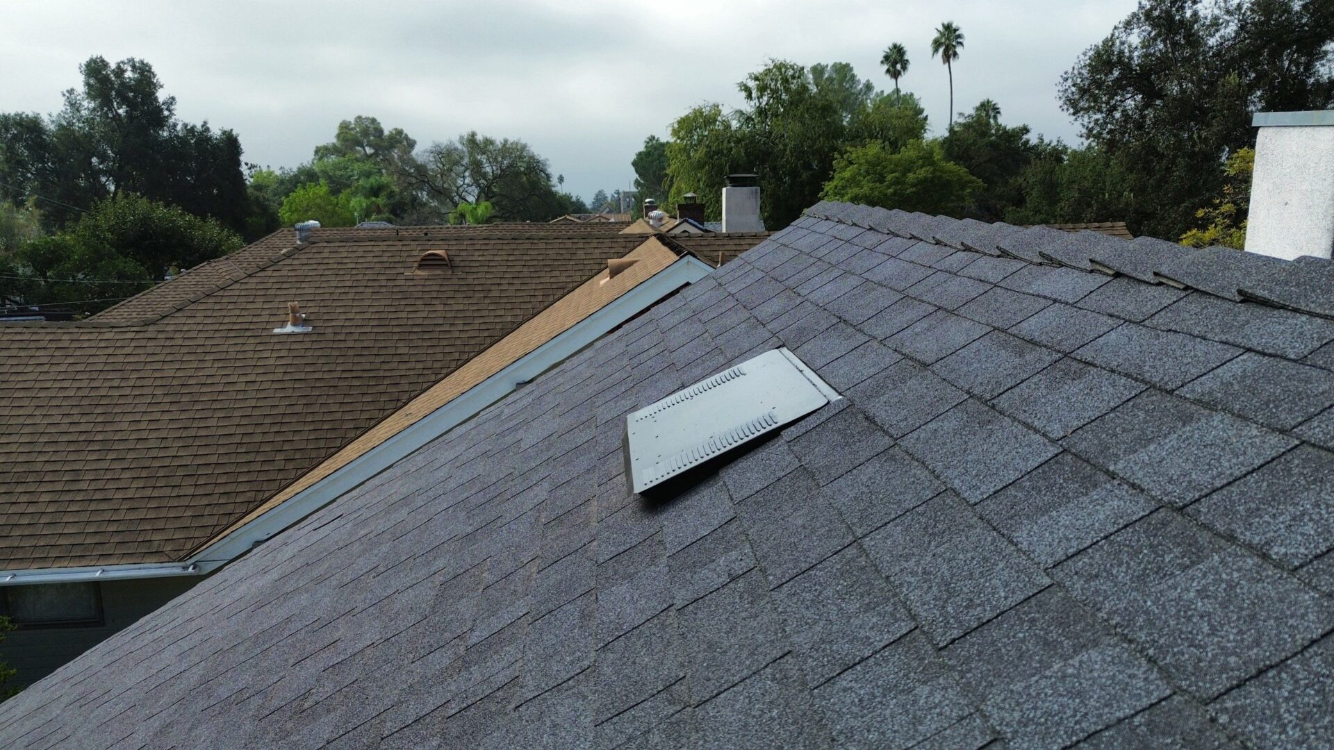 Roof with a solar panel and different shingle colors on each side.